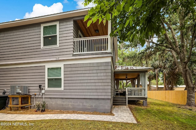 back of house featuring a balcony and a yard