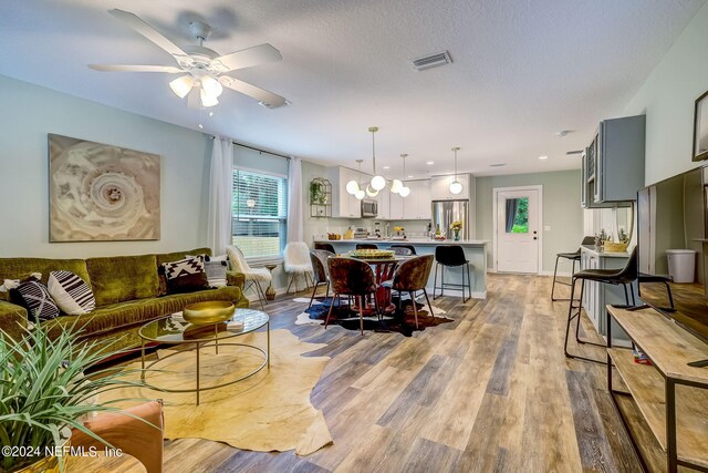 living room featuring hardwood / wood-style flooring, a textured ceiling, and ceiling fan