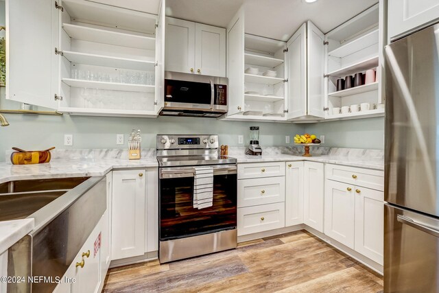 kitchen featuring white cabinetry, light hardwood / wood-style floors, light stone counters, and appliances with stainless steel finishes