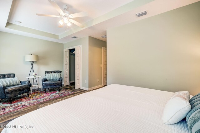 bedroom featuring ceiling fan, a raised ceiling, and hardwood / wood-style floors