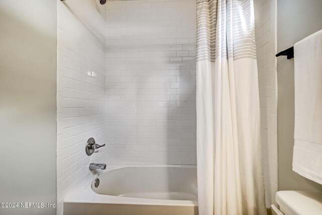 bathroom with toilet and shower / tub combo with curtain