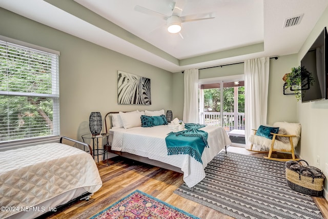 bedroom with hardwood / wood-style floors, multiple windows, and access to exterior