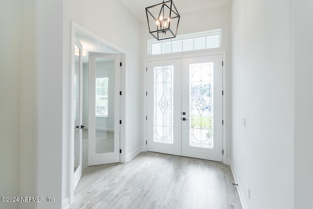 foyer featuring a chandelier, french doors, a healthy amount of sunlight, and light hardwood / wood-style floors