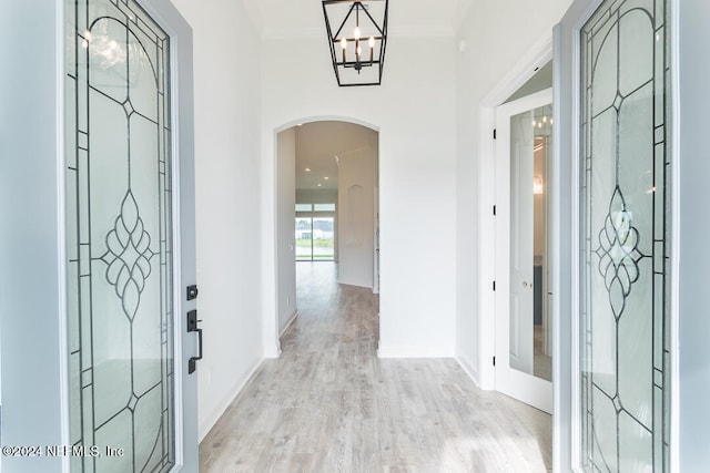 entrance foyer with a chandelier, ornamental molding, and light wood-type flooring