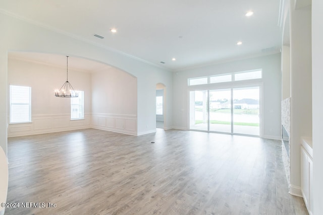 empty room with an inviting chandelier, ornamental molding, and light hardwood / wood-style flooring