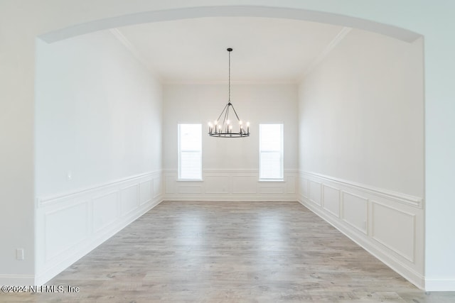 unfurnished dining area with crown molding, light hardwood / wood-style floors, and a notable chandelier