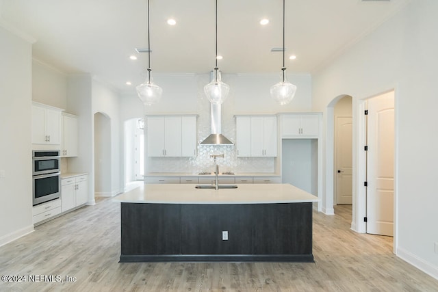 kitchen featuring hanging light fixtures, white cabinets, and an island with sink