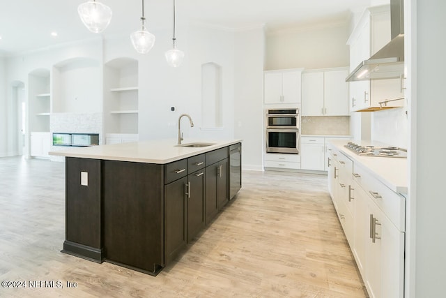 kitchen with dark brown cabinets, sink, a center island with sink, and light wood-type flooring