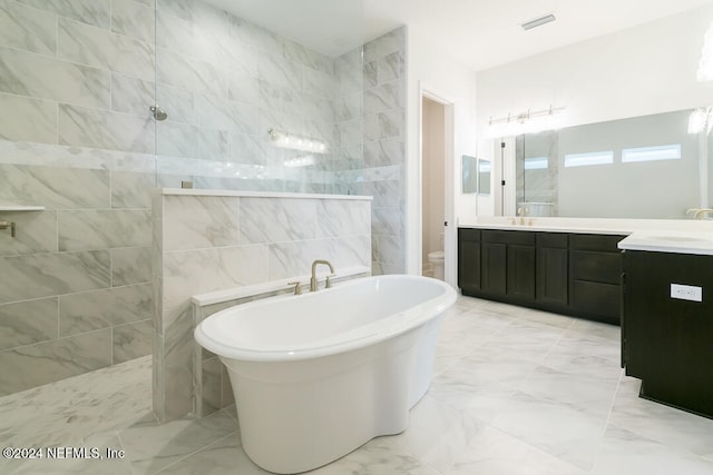 bathroom featuring vanity, independent shower and bath, and tile walls