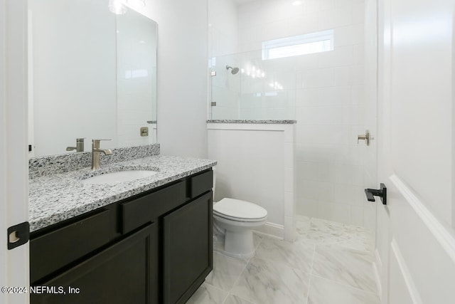 bathroom with tiled shower, vanity, and toilet