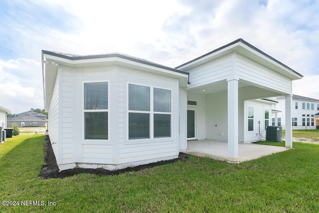 back of property with a patio area, a yard, and central AC