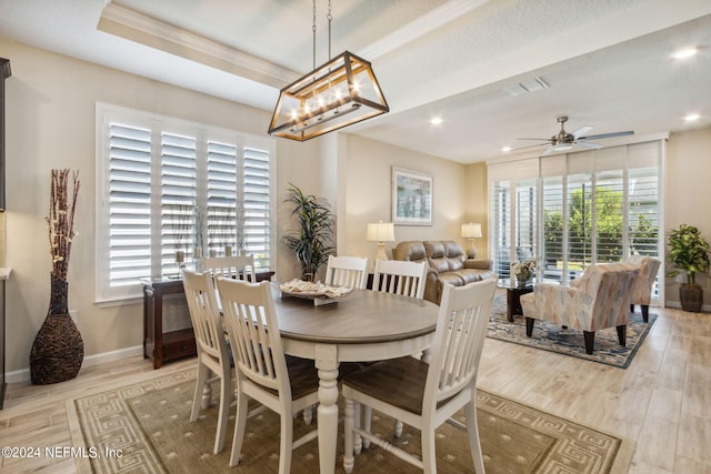 dining space with ceiling fan, a tray ceiling, light hardwood / wood-style flooring, and plenty of natural light