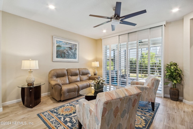 living room featuring expansive windows, ceiling fan, and light wood-type flooring