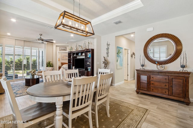 dining area with ceiling fan with notable chandelier, light hardwood / wood-style floors, a raised ceiling, and a textured ceiling