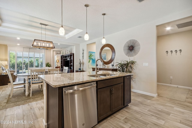 kitchen featuring a tray ceiling, hanging light fixtures, light wood-type flooring, sink, and dishwasher