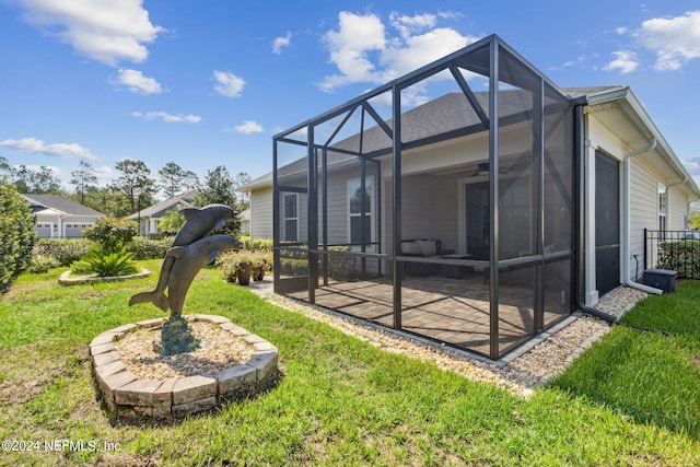 rear view of property featuring a lanai, a patio, a yard, and ceiling fan