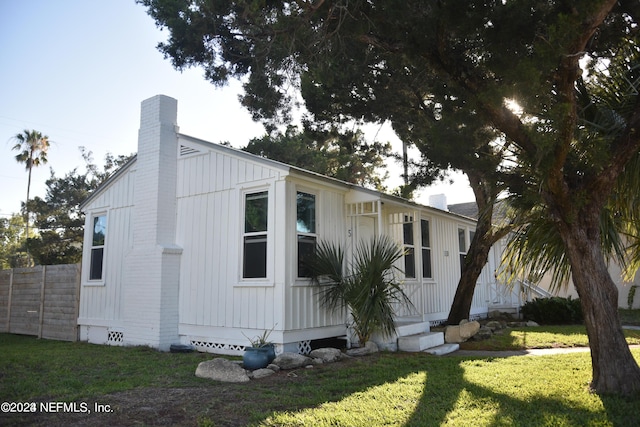 view of home's exterior with entry steps, a lawn, a chimney, crawl space, and fence