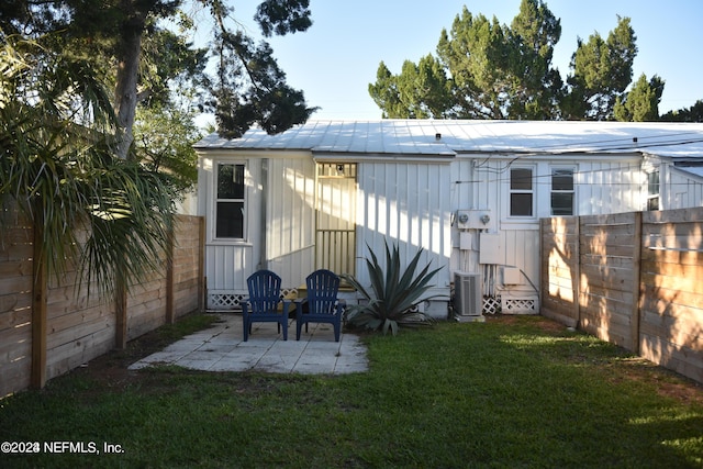 rear view of house featuring a yard, a patio area, central AC, metal roof, and a fenced backyard