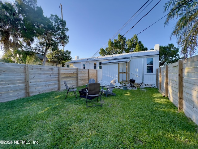 rear view of house featuring a fenced backyard, a lawn, and an outbuilding