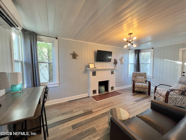 living room featuring a fireplace, plenty of natural light, wood finished floors, and an inviting chandelier