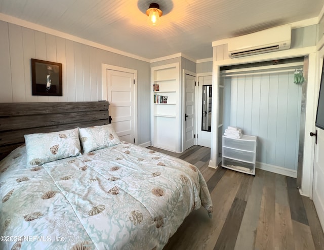 bedroom featuring dark wood-type flooring, a wall unit AC, ornamental molding, and baseboards