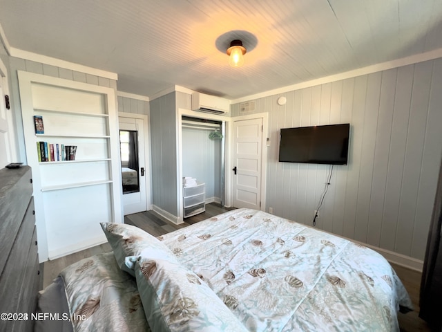 bedroom with a closet, an AC wall unit, visible vents, and wood finished floors