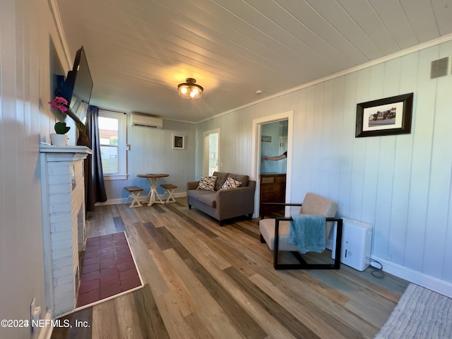 living area with visible vents, ornamental molding, wood finished floors, a wall mounted air conditioner, and baseboards