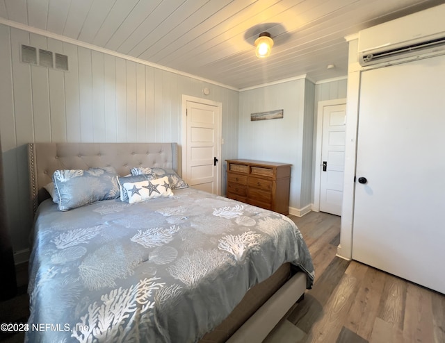 bedroom with a wall mounted AC, wooden ceiling, wood finished floors, and visible vents