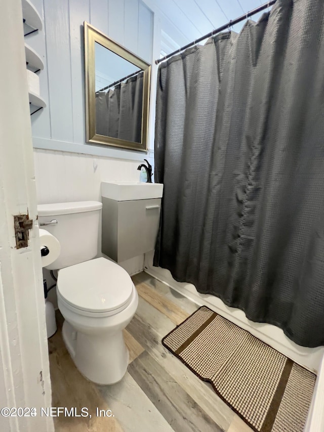 bathroom with toilet, a shower with curtain, and wood finished floors