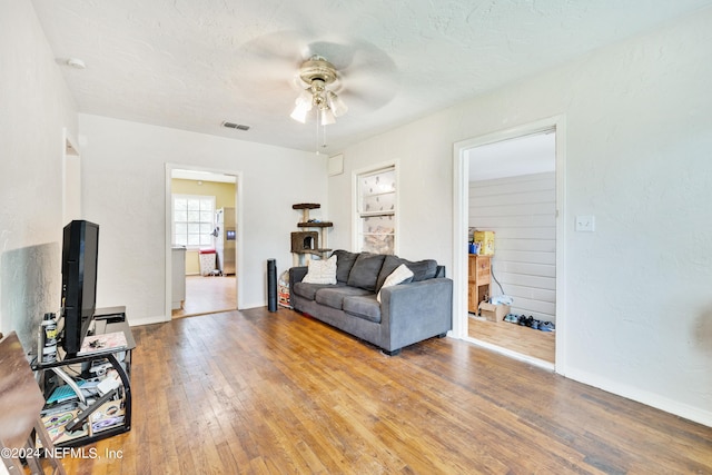 living room with a textured ceiling, light hardwood / wood-style flooring, and ceiling fan