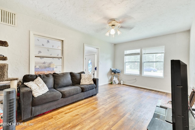 living room featuring ceiling fan, hardwood / wood-style floors, and a textured ceiling