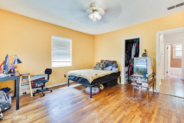 bedroom featuring ceiling fan, light hardwood / wood-style flooring, multiple windows, and a closet