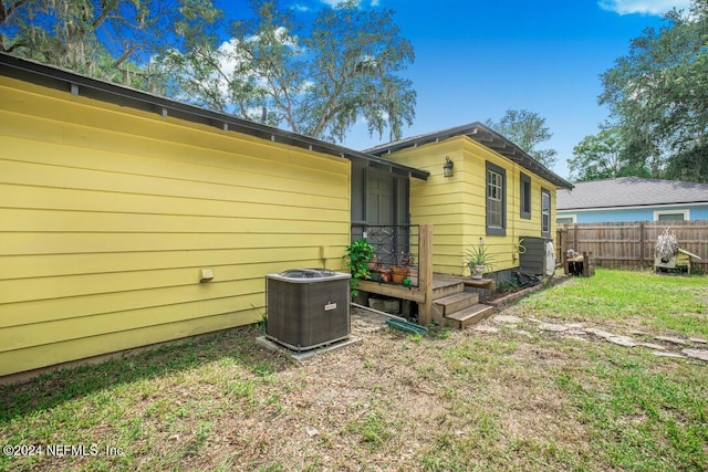 view of side of home with central AC and a yard