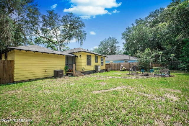 rear view of property with a lawn and cooling unit