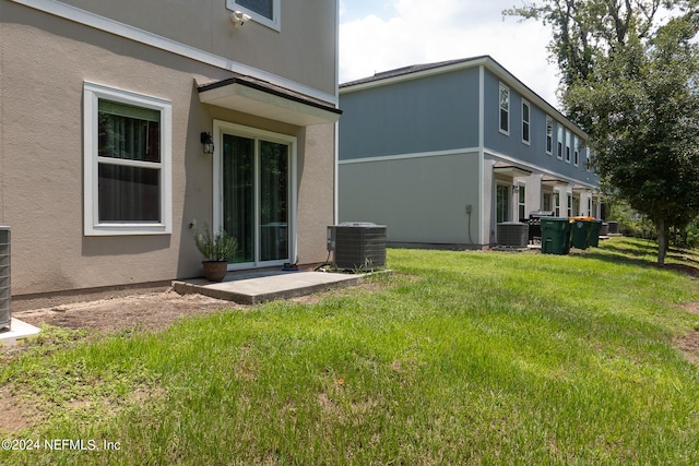 rear view of property with central air condition unit and a lawn