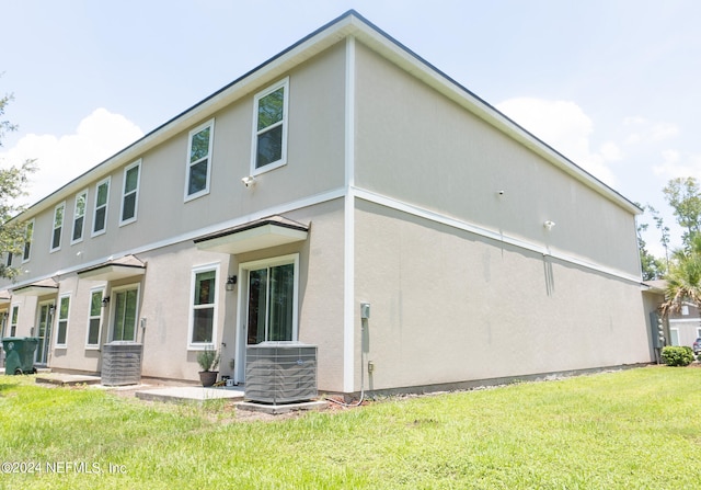 rear view of house with central AC and a lawn