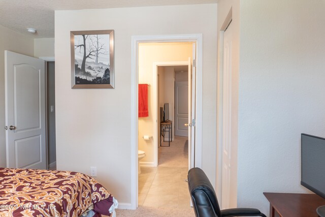 bedroom featuring ensuite bath and light tile patterned floors