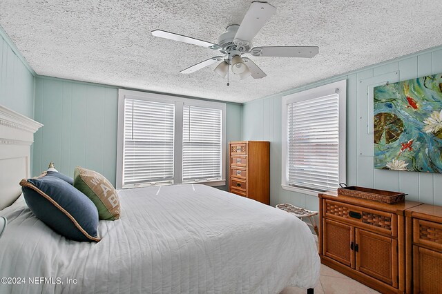 bedroom featuring ceiling fan, light tile patterned floors, and a textured ceiling