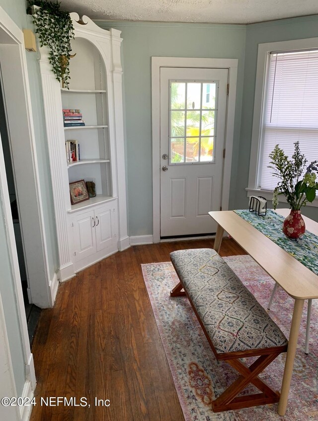 doorway to outside with built in features, a textured ceiling, and dark hardwood / wood-style floors