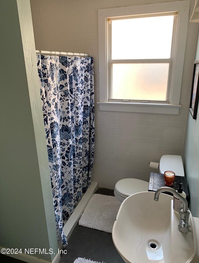 bathroom featuring sink, toilet, tile patterned floors, and tile walls