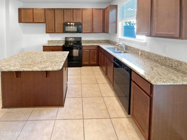 kitchen featuring sink, a kitchen bar, light tile patterned floors, light stone counters, and black appliances