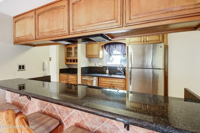 kitchen with dark stone counters, sink, custom range hood, a breakfast bar, and appliances with stainless steel finishes