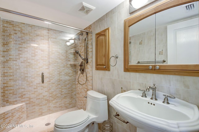 bathroom featuring a stall shower, visible vents, decorative backsplash, a sink, and tile walls