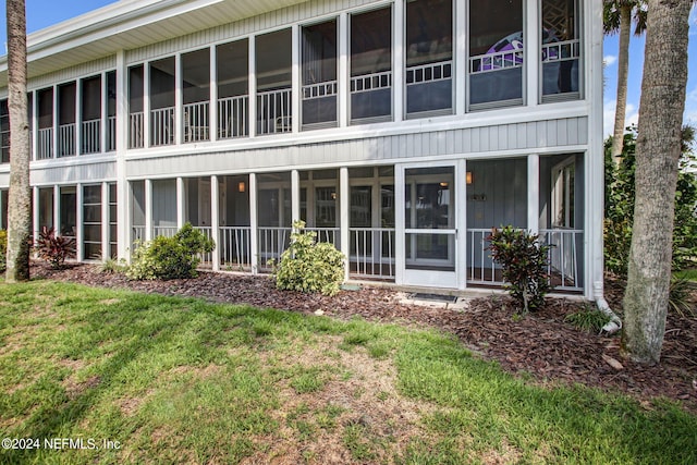 back of house featuring a sunroom and a lawn