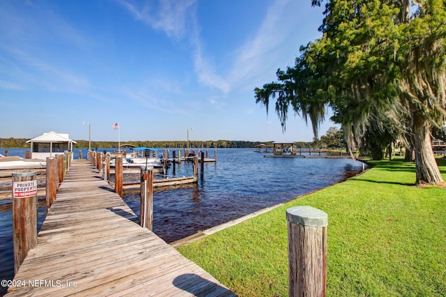 view of dock with a water view and a yard