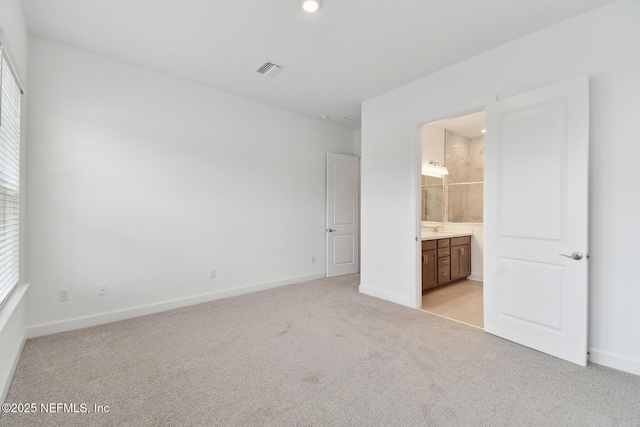 unfurnished bedroom featuring light carpet and ensuite bath