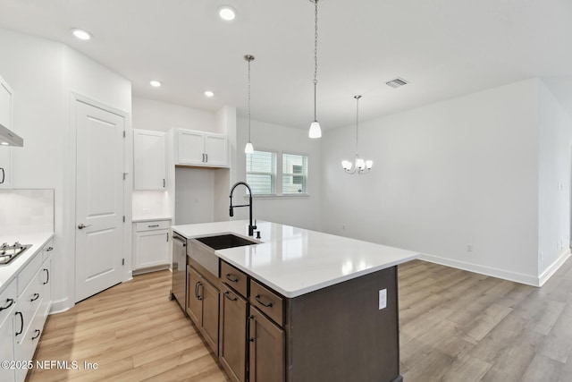 kitchen featuring light hardwood / wood-style flooring, pendant lighting, dishwasher, sink, and white cabinetry