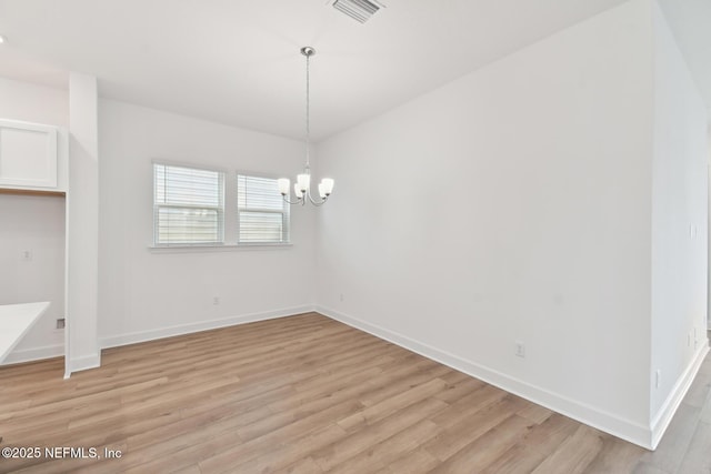 unfurnished dining area featuring light hardwood / wood-style flooring and an inviting chandelier