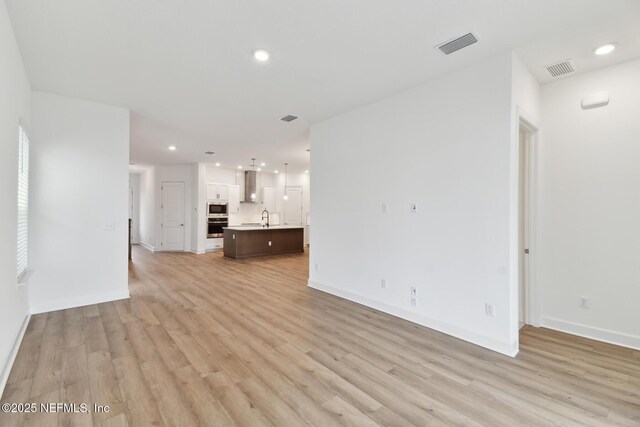 unfurnished living room featuring light hardwood / wood-style floors and sink