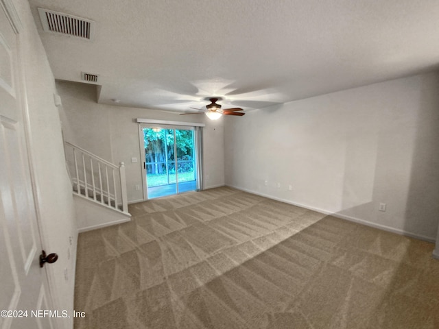 carpeted spare room featuring ceiling fan and a textured ceiling